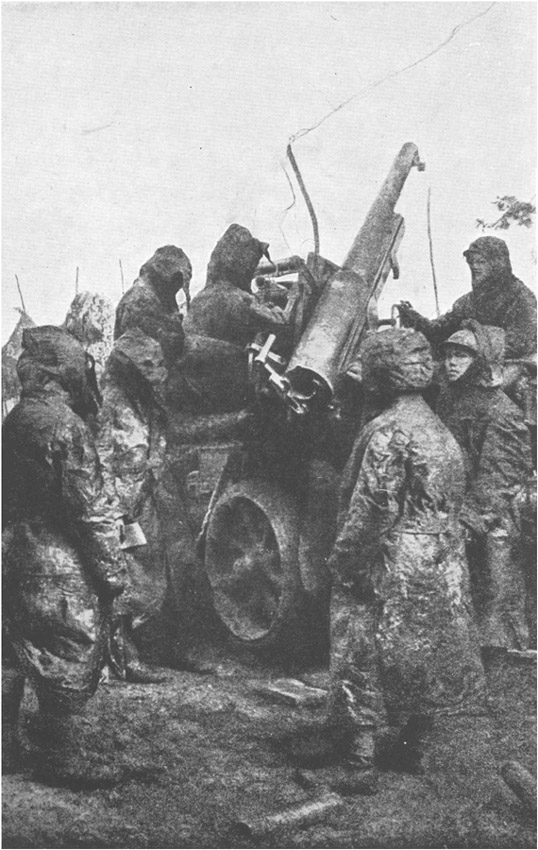 Camouflaged troops wearing gas masks, and manning an artillery piece.